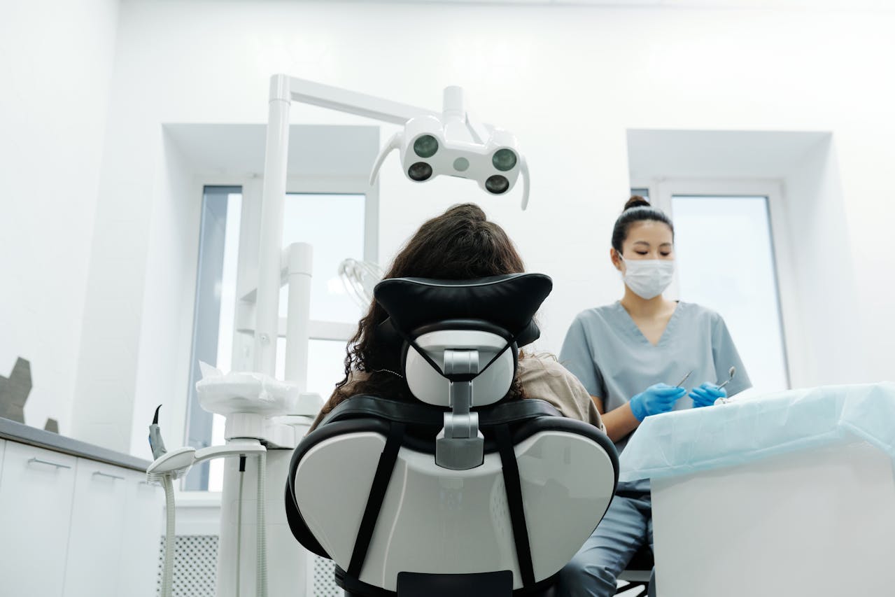 Dental Schedule: Optimize Your Practice 1 Patient in a dental chair with dentist preparing tools