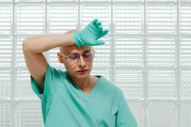 tired dentist wearing a green gloves and a scrub suit