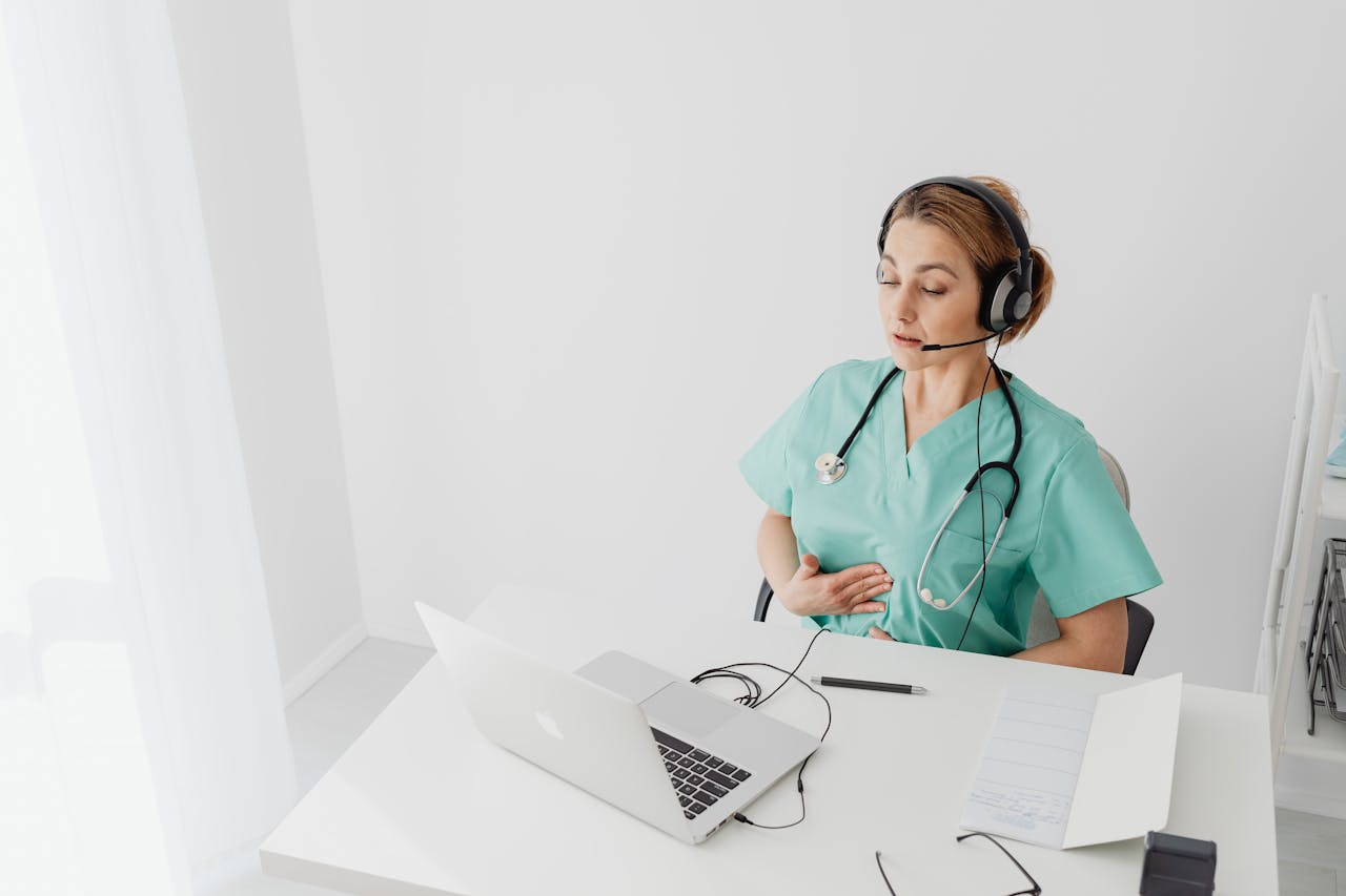 dentist wearing a headset talking with somebody online and a laptop in front of her